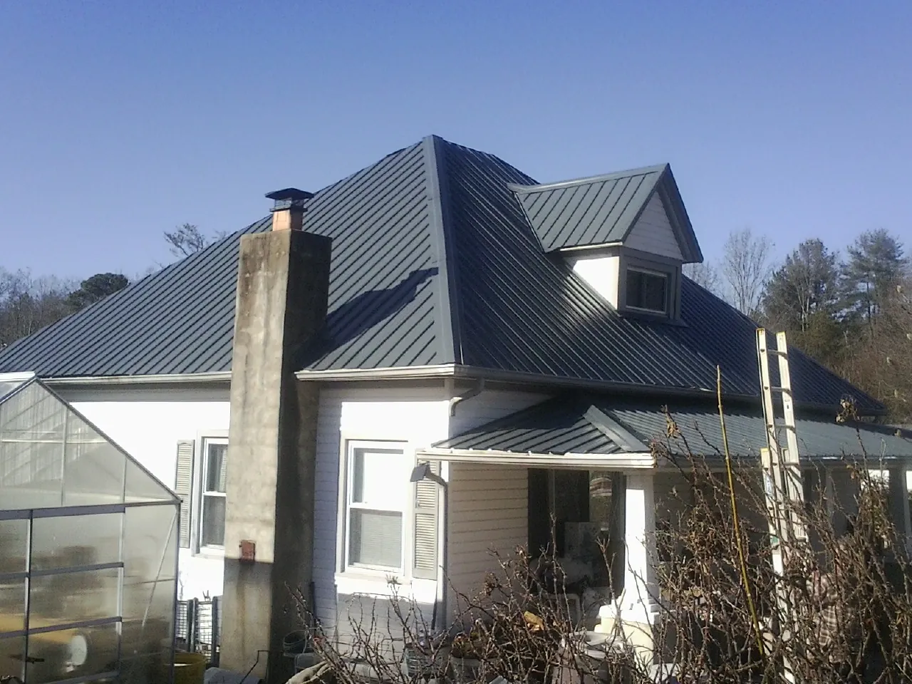 Dark blue standing seam metal roof on a white farmhouse with dormer — Slate & Tile Roof Repair by Roofing Brothers in Rhinebeck