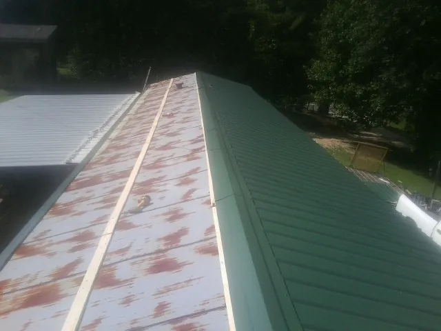 Old rusted panels beside newly installed green metal roofing — Wind Damage Roof Repair by Roofing Brothers in Rhinebeck
