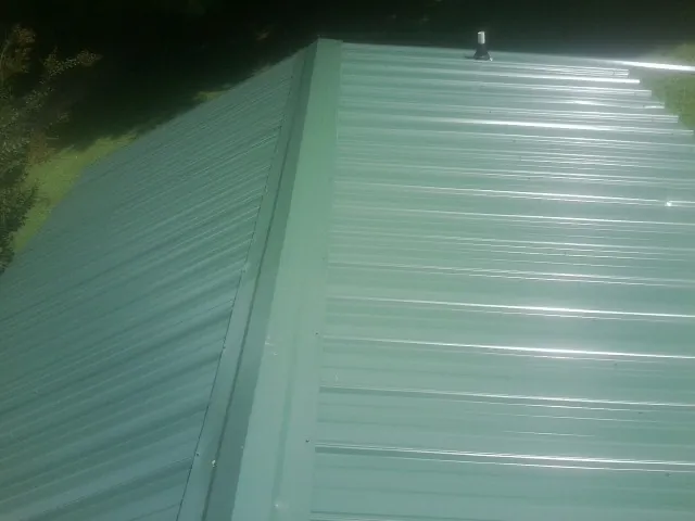 New green metal panels meeting at the ridge of a roof — Flat Roof Repair work by our crew in Rhinebeck