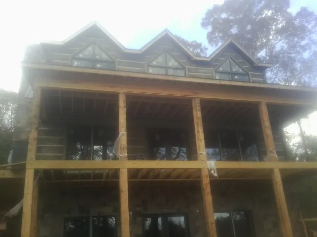 Dormers and porch framing on a large log home under construction — Roof Coating work by our crew in Rhinebeck