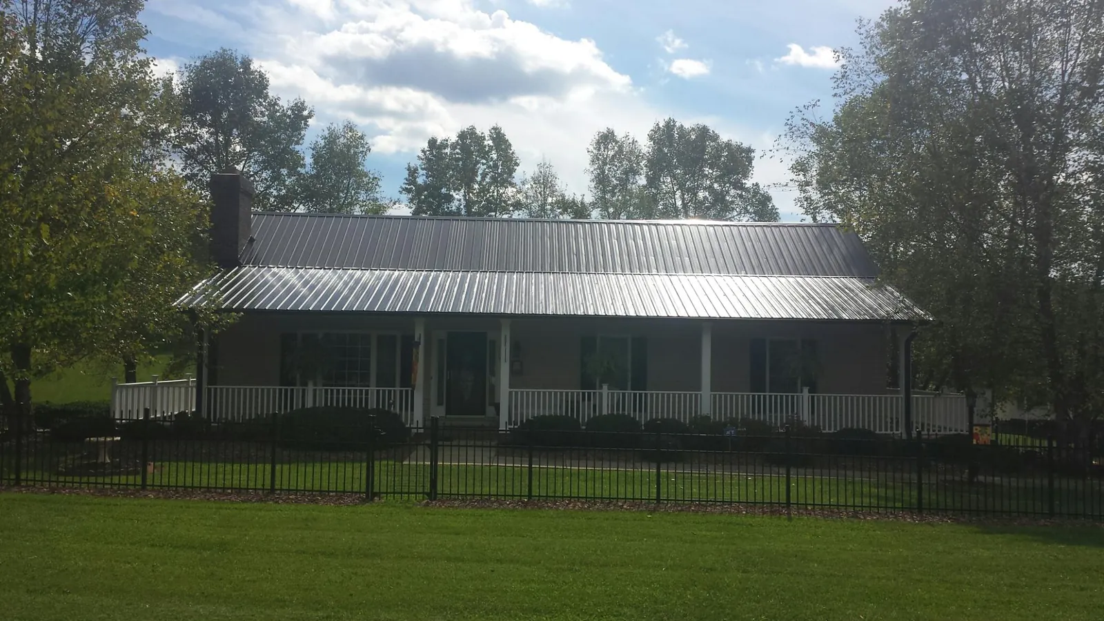 Gray metal roof on a brick ranch with a full width front porch — Gutter Guard Installation work by our crew in Rhinebeck
