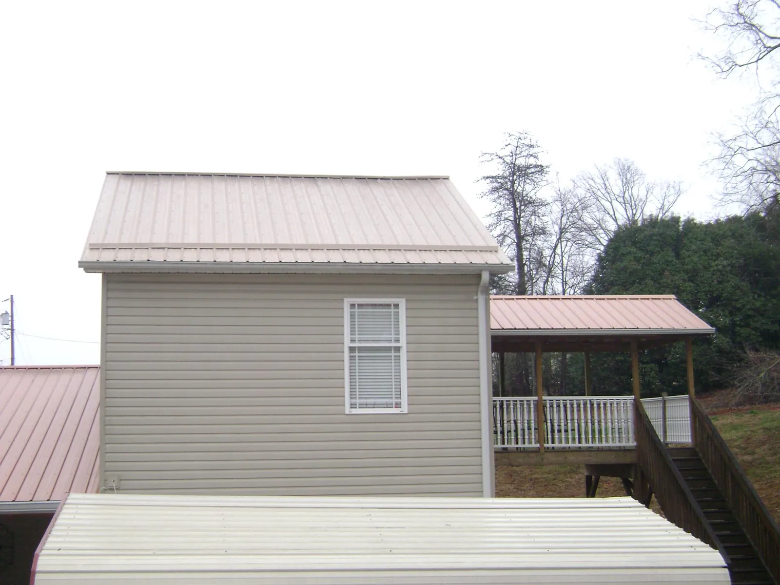Tan metal roofs on a two story addition and attached porch, from a Roof Replacement job in Rhinebeck