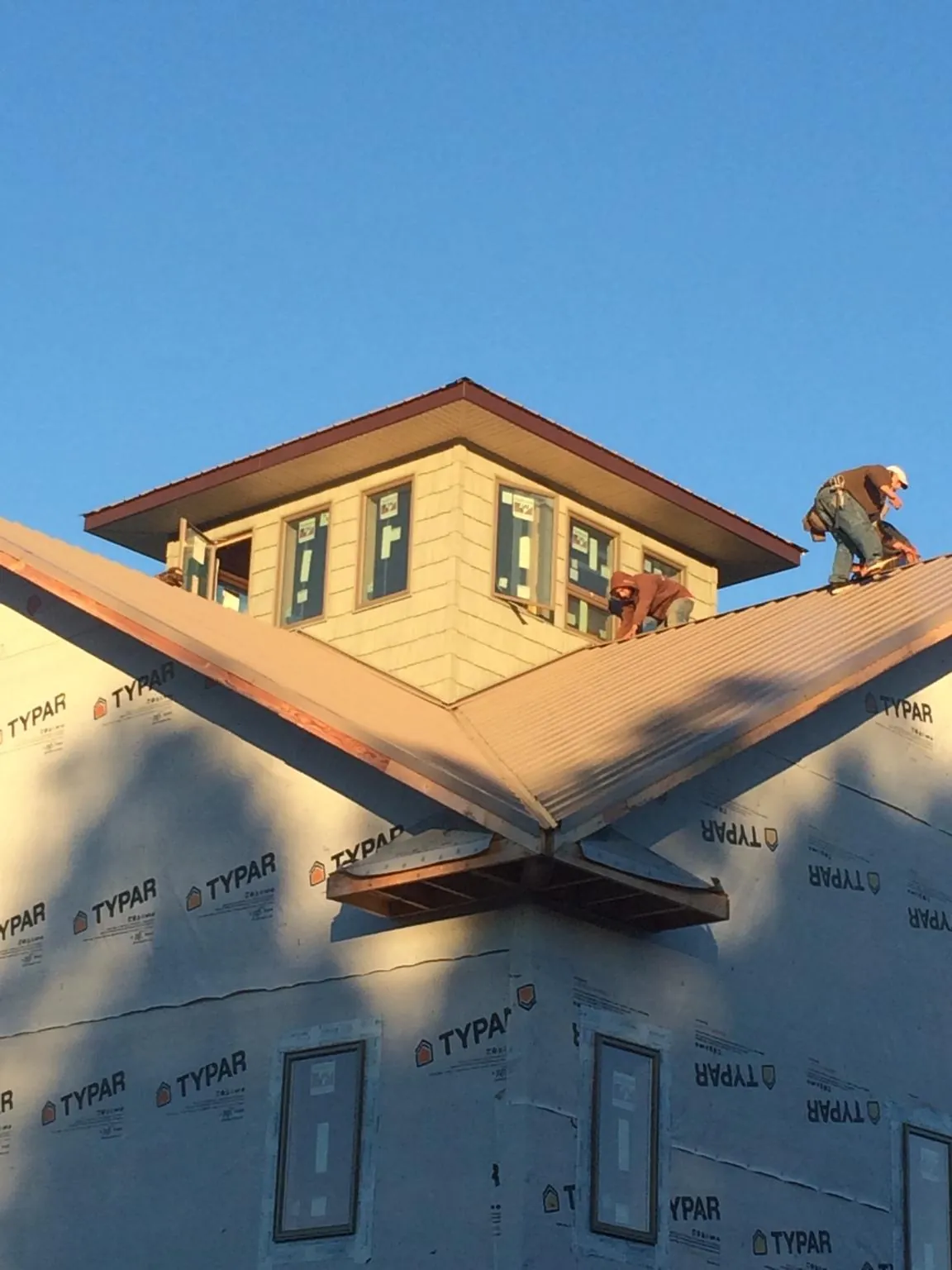 Roofers working around a rooftop cupola on a new metal roof at sunset — Roof Waterproofing in Rhinebeck by Roofing Brothers